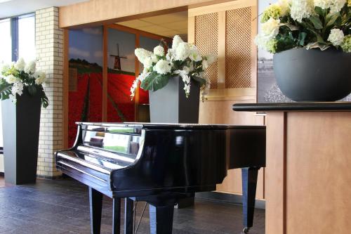 a black piano with a vase of flowers on it at Best Western Plus Amsterdam Airport Hotel in Hoofddorp