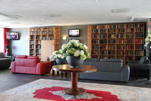 a living room with a couch and a vase of flowers on a table at Best Western Plus Amsterdam Airport Hotel in Hoofddorp