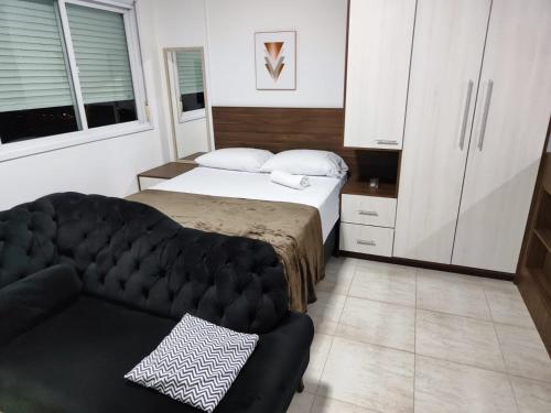 a small bedroom with a bed and a couch at Loft Central in Passo Fundo