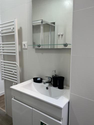 een witte badkamer met een wastafel en een spiegel bij PÉROLA DA ARRÁBIDA - no coração de Setúbal in Setúbal