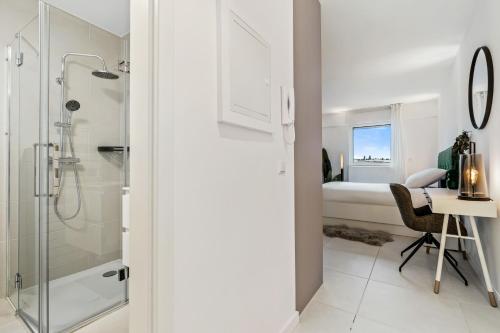 a bathroom with a shower and a desk and a bed at Stylish Studio with King Bed, Balcony and Full Kitchen in Luxembourg