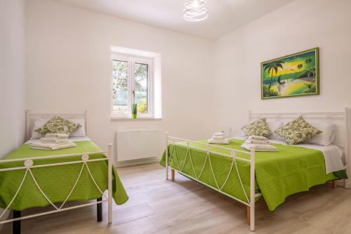 two beds in a white room with green sheets at La Villa - Rainbow House in Martina Franca