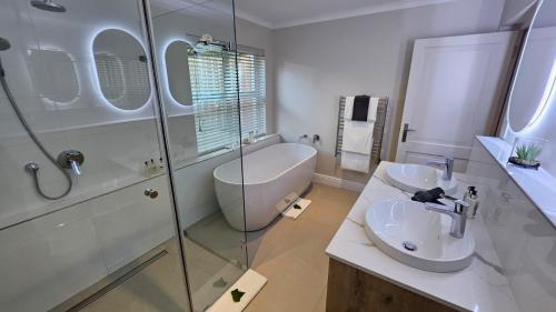 a bathroom with a tub and a sink and a shower at Vredenburg Manor House in Somerset West