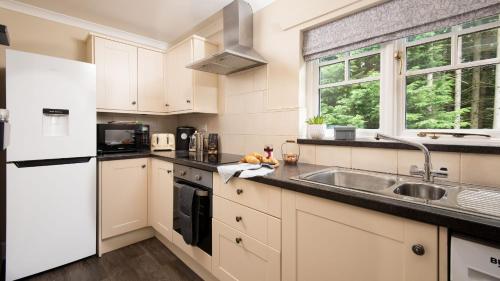 a kitchen with white cabinets and a sink at East Lodge at Ashiestiel in Clovenfords