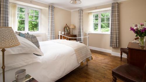 a bedroom with a white bed and two windows at East Lodge at Ashiestiel in Clovenfords