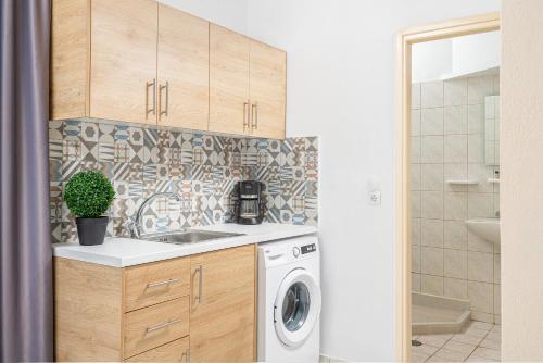 a kitchen with a sink and a washing machine at Mylos Apartments Anissaras in Hersonissos
