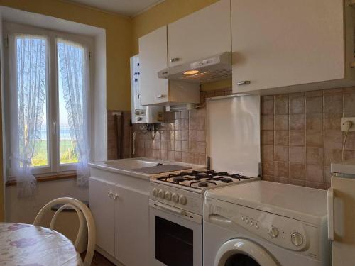 une cuisine avec une cuisinière blanche four supérieur à côté d'une fenêtre dans l'établissement 491 - Maison unique, les pieds dans l'eau, le long de la plage de Saint-Pabu, à Erquy