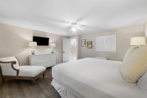 a white bedroom with a bed and a chair at Eastern Shores on 30A by Panhandle Getaways in Seagrove Beach