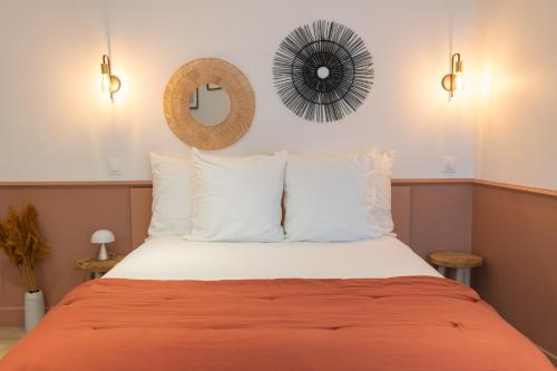 ein Bett mit weißen Kissen und einem Spiegel an der Wand in der Unterkunft Le Logis d'Origine. in Marly-le-Roi