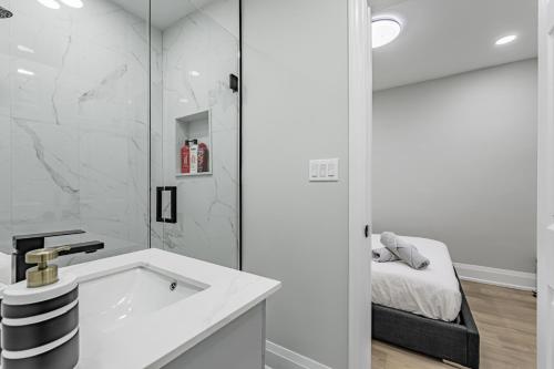 - une salle de bains blanche pourvue d'un lavabo et d'un lit dans l'établissement Victoria Park Suite, à Toronto