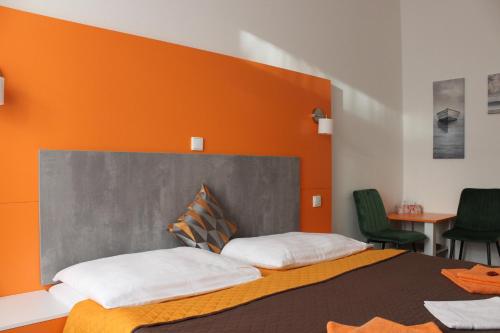 - une chambre avec un grand lit et un mur orange dans l'établissement Apartments Verona Karlovy Vary, à Karlovy Vary