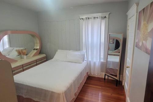 a small bedroom with a white bed and a mirror at Modern Haven ,Your Stylish Retreat in Boston