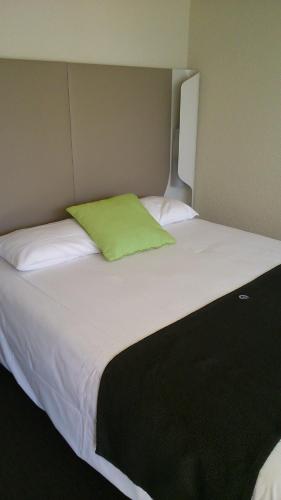 a large white bed with a green pillow on it at Hotel Campanile Besançon Nord Ecole Valentin in Besançon
