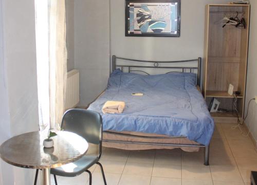 ein Bett mit blauer Decke und einem Tisch in einem Zimmer in der Unterkunft Stunning one Bedroom Studio in thessaloniki in Thessaloniki