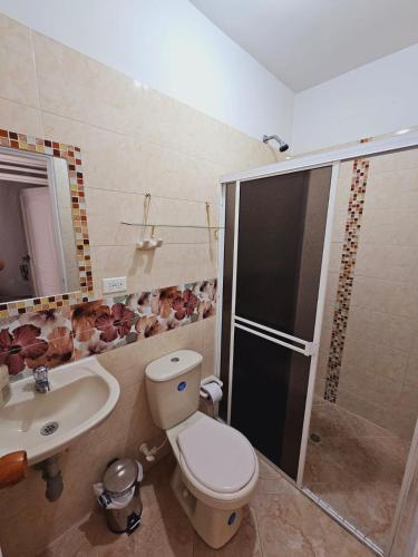 Un baño con inodoro, lavabo y ducha. en comodo apartamento central, en Buga