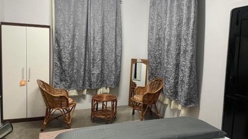 a bedroom with a bed and chairs and curtains at HeiJo's Homestay in Jowai