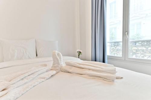 - un lit blanc avec des draps blancs et une fenêtre dans l'établissement Appartement proche Mairie 10ème arrondissement, à Paris