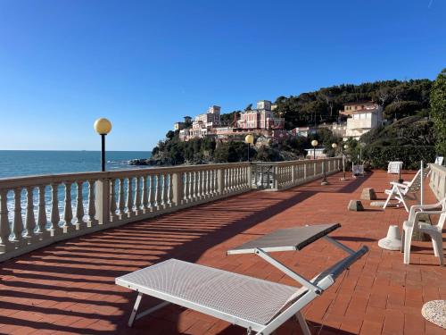 um deque com cadeiras e o oceano e edifícios em Residence Mediterraneo - Baia del Quercetano em Castiglioncello