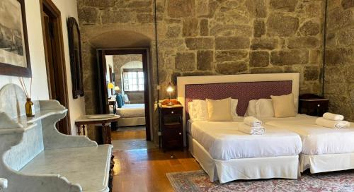 a bedroom with two beds and a stone wall at Pazo de San Pedro de Bembibre in Taboada