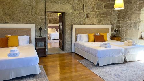 two beds in a room with a stone wall at Pazo de San Pedro de Bembibre in Taboada