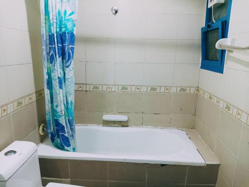 uma banheira na casa de banho com uma cortina de chuveiro azul em Master Room With Attached Washroom For You em Ajman