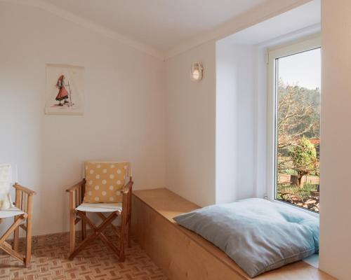 a bedroom with a bed and a chair and a window at Quinta da Quinhas in Vila Praia de Âncora