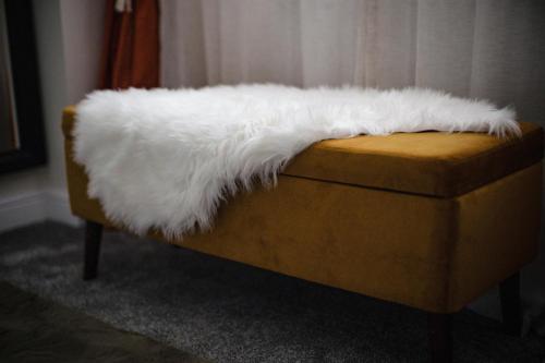 a white faux fur laying on top of a couch at Leeds getaway with hot tub & gaming room in Wakefield