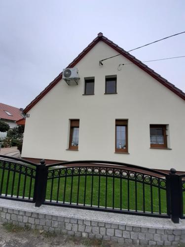 ein weißes Haus mit einem schwarzen Zaun in der Unterkunft Noclegi Dobrzeń Wielki in Dobrzeń Wielki