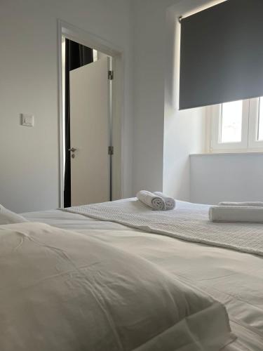 a white bedroom with a bed with two towels on it at PÉROLA DO BOCAGE - no coração de Setúbal in Setúbal