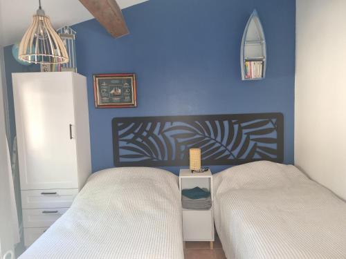 une chambre avec deux lits et un mur bleu dans l'établissement coustelline, au Lavandou