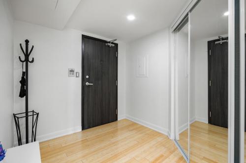 an empty room with a black door and wooden floors at Modern 2-Bedroom Condo w Floor to Ceiling Windows in Toronto