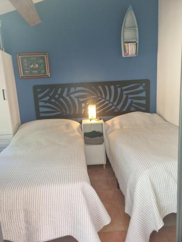 2 camas en un dormitorio con una pared azul en coustelline, en Le Lavandou