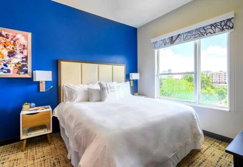 a large white bed in a blue room with a window at Private Downtown Apartment With City View in Raleigh