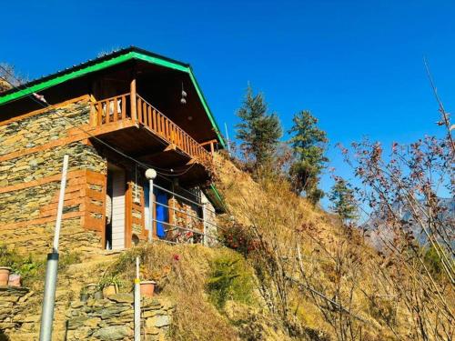 a log cabin on a hill with a balcony at Woodstone Farmstay in Sainj