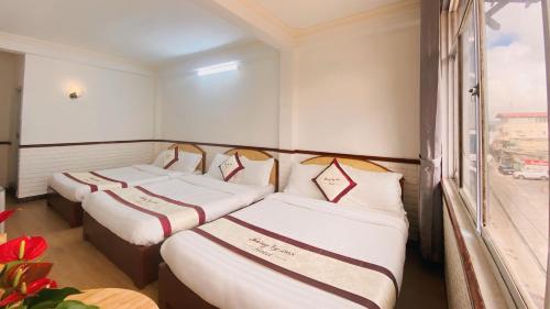 drei Betten in einem Zimmer mit Fenster in der Unterkunft Tường Vy Dalat Central in Da Lat