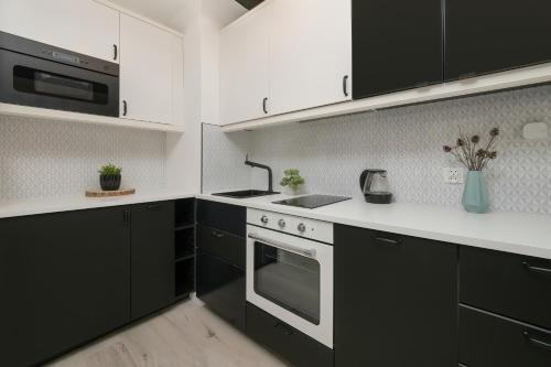 a kitchen with black cabinets and white counter tops at Modern Studio Wróblewskiego with Balcony and Free Parking by Renters in Łódź