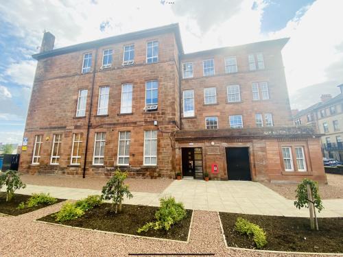 un gran edificio de ladrillo con un patio delante de él en North Kelvin Guest House en Glasgow