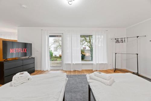 a white room with two beds and a tv at W01 Große Wohnung für Teams in Wendlingen am Neckar