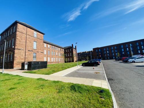 un grande edificio in mattoni con auto parcheggiate in un parcheggio di North Kelvin Guest House a Glasgow