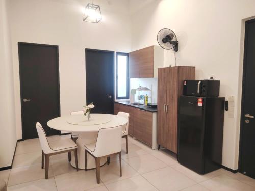 eine Küche mit einem Tisch und Stühlen sowie einem Kühlschrank in der Unterkunft Sweet Stay in Jelutong