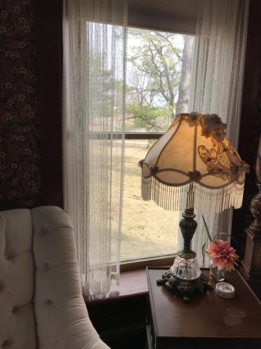 una lámpara sentada en una mesa junto a una ventana en The Nauvoo Grand Bed & Breakfast en Nauvoo