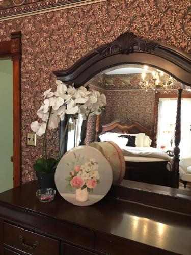 a dresser with a mirror and a plate with flowers on it at The Nauvoo Grand Bed & Breakfast in Nauvoo