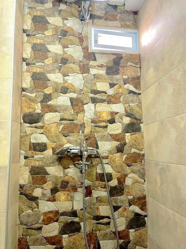 La salle de bains est pourvue d'un mur en pierre et d'une douche. dans l'établissement Sunny apartment 1, à Serres