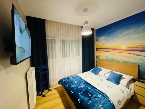 a bedroom with a bed with a painting on the wall at Sunset Resort Apartament Marco Marina in Grzybowo