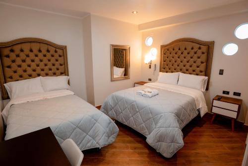 Habitación de hotel con 2 camas y mesa en Hotel Melthon Urbans, en Ayacucho