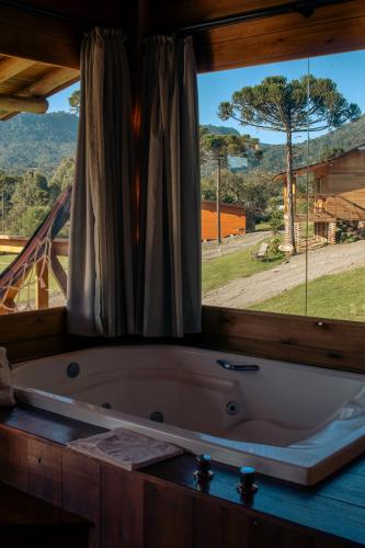 a bath tub in a room with a window at Hospedaria Refugio do Invernador in Urubici
