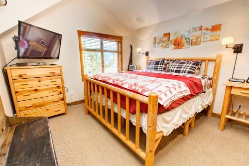um quarto com uma cama de madeira e uma televisão numa cómoda em Mountain Star em Whistler