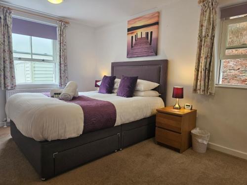 a bedroom with a large bed with purple pillows at Bespoke coastal 2 bed cottage with free parking in Ilfracombe
