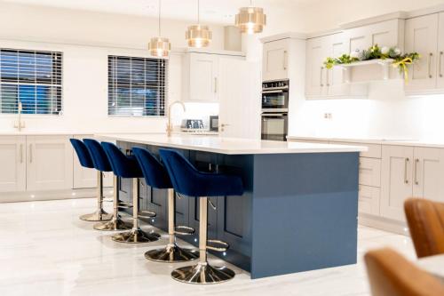 a white kitchen with a blue island with bar stools at Newtown House in Newry