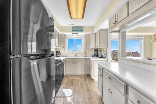 a kitchen with white cabinets and a black refrigerator at Sea-Nic View in Caswell Beach